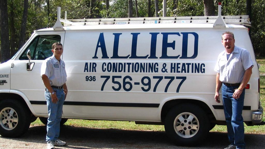 Two Allied Air Conditioning & Heating technicians standing beside their company service van, phone number 936-756-9777